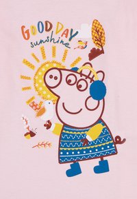 Cerdito de dibujos animados que lleva un vestido azul con una manga amarilla, sosteniendo un pájaro, rodeado de rayos de sol, flores y texto sobre un fondo rosa.