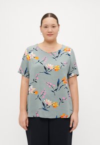 Blommig kortärmad topp i ljusgrön tyg. Har färgglada blommor i rosa, orange och gult med mörka blad; rund halsringning och avslappnad passform.