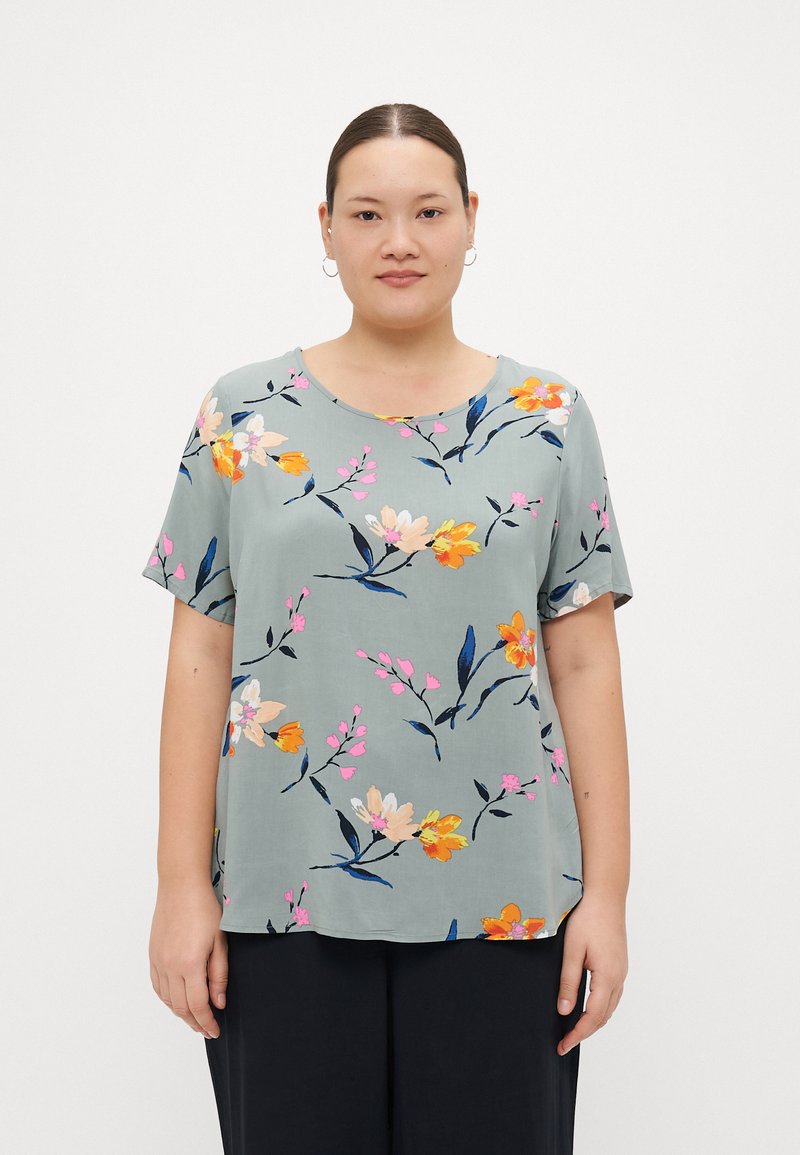 Blommig kortärmad topp i ljusgrön tyg. Har färgglada blommor i rosa, orange och gult med mörka blad; rund halsringning och avslappnad passform.