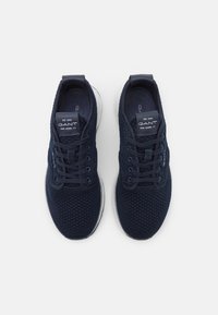 Navy blue mesh athletic shoes with a white sole, featuring a rounded toe, lace-up front, and a logo tag on the tongue.