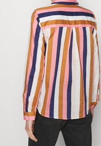 Randig skjorta med vertikala mönster i rosa, vitt, marinblått och orange, med krage, knappmanschetter och plissering på baksidan.