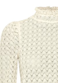 Vit spetsblus med hög krage och volangkanter, intrikata hjärtformade mönster och långa ärmar med ömtålig textur.