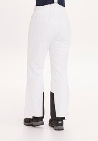 Witte waterdichte skibroek met een zwart zijpaneel, elastische tailleband en verstelbare banden, ontworpen voor sneeuwsporten en buitenactiviteiten.