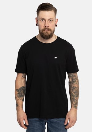 Zwarte katoenen T-shirt met een ronde hals, korte mouwen en een klein wit berenlogo op de borst. Draagt met een blauwe spijkerbroek.