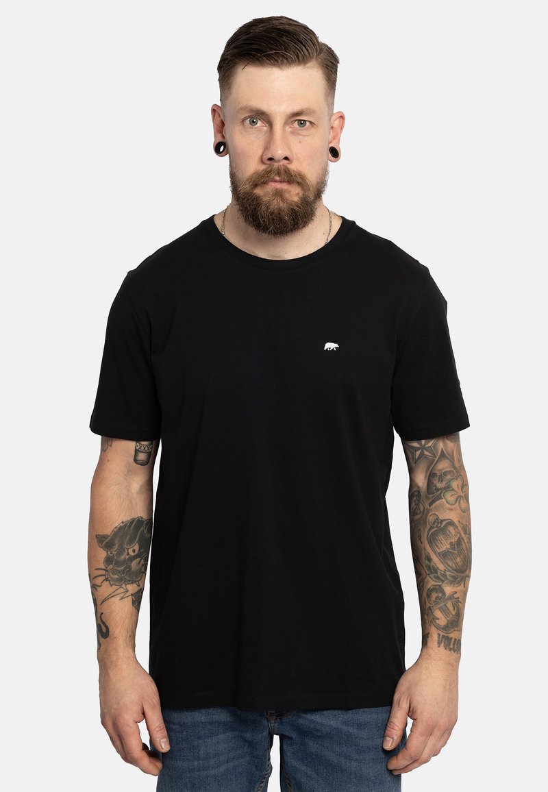 Zwarte katoenen T-shirt met een ronde hals, korte mouwen en een klein wit berenlogo op de borst. Draagt met een blauwe spijkerbroek.