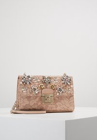 Borsa a mano in pizzo rosa con decorazioni floreali, chiusura oro, tracolla a catena e superficie testurizzata. Presenta vari gemelli a forma di fiore.