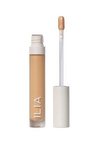 Flytande concealer i en genomskinlig tube med en beige nyans. Har ett vitt lock och en applikatorpinne med en mjuk, texturerad spets.