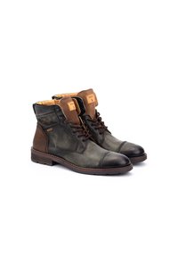 Botas de tobillo marrones y olivo hechas de cuero y ante, con un cuello acolchado, cierre de cordones en la parte delantera y panel lateral texturizado. Suela de goma.
