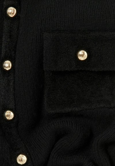Cardigan nero lavorato a maglia con tasca a patch testurizzata e bottoni dorati. Il tessuto ha una texture morbida e a coste.