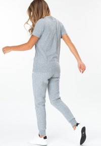 Grijze katoenen T-shirt en bijpassende sweatpants, beide met een gladde textuur. De outfit heeft een klassieke ronde hals en ribbelmanchetten.