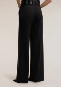Czarne spodnie o szerokich nogawkach wykonane z gładkiego materiału, z wysokim stanem, wyposażone w kieszenie i prosty krój, wykończone eleganłym obszyciem.