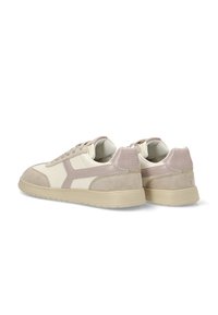 Zapatillas que combinan cuero beige claro y ante topo. El diseño incluye un logotipo lateral en contraste y acentos texturizados.