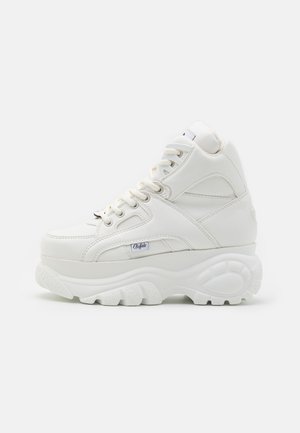 Baskets montantes blanches en cuir texturé avec une semelle blanche épaisse, dotées d'un système de laçage et d'un branding discret sur le côté.