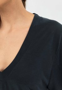 T-shirt a V profondo di colore blu navy scuro realizzato in un tessuto leggero e morbido. Presenta una vestibilità comoda e maniche corte, mettendo in risalto un design semplice e classico.