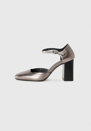 Chaussure à talon aiguille gris foncé métallisé avec un bout pointu et une lanière de cheville. Dispose de détails perforés et d'un talon épais noir.