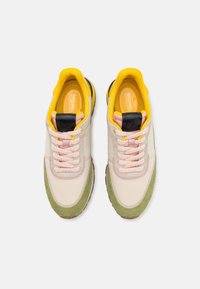Baskets élégantes avec tige synthétique beige, accents en daim vert, col jaune, lacets roses et détail noir au talon. Intérieurs doux.