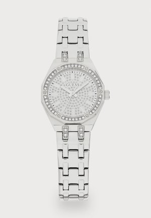 Montre octogonale argentée avec un cadran argenté texturé et scintillant. Le bracelet comporte de grands segments liés et des embellissements en cristal.