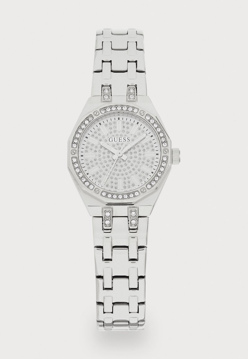 Montre octogonale argentée avec un cadran argenté texturé et scintillant. Le bracelet comporte de grands segments liés et des embellissements en cristal.