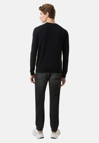 Granatowy sweter dzianinowy z długimi rękawami, okrągłym dekoltem i dopasowanymi mankietami, w połączeniu z ciemnoszarymi jeansami i białymi tenisówkami. Minimalne detale.