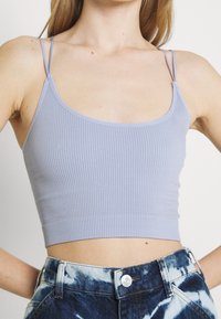 Ljuslila räfflad crop top med tunna band och rak halsringning, som parats ihop med batikfärgade denimshorts med knappstängning.