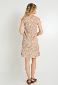 Vestido sin mangas de color beige con un patrón de cebra, textura de tela suave y diseño acampanado, complementado con sandalias de tiras marrones.