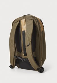 Olive green backpack with padded shoulder straps, mesh back panel, and adjustable chest strap. Features a structured design and durable material.