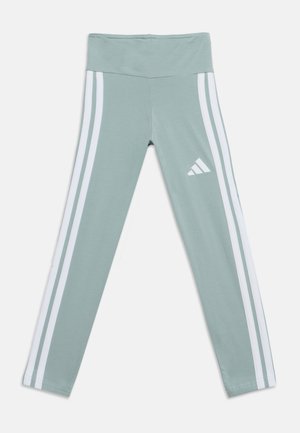 Leggings de sport vert clair avec des bandes blanches sur les côtés et un logo Adidas blanc sur la partie supérieure de la cuisse, posés à plat sur fond blanc.