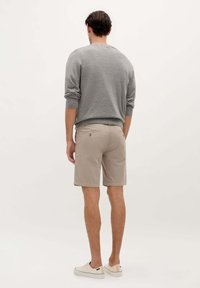 Suéter gris de punto, pantalones cortos beige, ajuste casual, textura suave, longitud corta y zapatillas de color claro. Diseño minimalista sin patrones visibles.