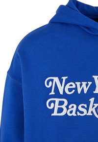 Niebieska bluza z kapturem wykonana z miękkiego materiału, z białym haftowanym napisem "New York Basketball" na froncie, z kapturem na sznurku.