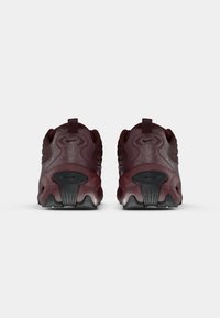 Nike batai tamsiai bordeaux spalvos su tekstūruotomis plokštėmis, apvalia forma, juodais akcentais ir matoma oro pagalvė ant pado.