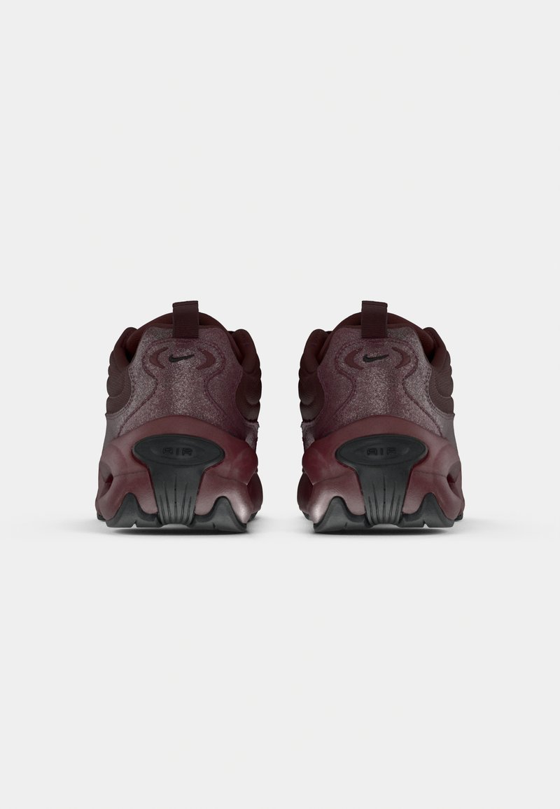 Zapatillas Nike en burdeos oscuro con paneles texturizados, forma redondeada, detalles en negro y una unidad de amortiguación de aire visible en la suela.