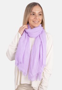 Écharpe lilas en tissu texturé, avec des bords bruts et un tissage lâche, drapée autour du cou de manière décontractée.