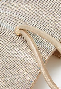 Sac à main doré brillant avec une surface texturée recouverte de petites paillettes iridescentes, doté de sangles en satin doré clair et d'un détail de fermoir rond.
