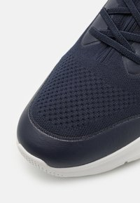 Sneaker blu navy con upper in rete dotato di perforazioni testurizzate e dettagli in pelle, suola in gomma bianca e lacci piatti blu navy.