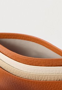 Δερμάτινο παπούτσι με στρογγυλεμένο, χαμηλό κόψιμο. Διαθέτει πορτοκαλί εξωτερικό και δύο κρεμ ρίγες κατά μήκος της άκρης. Ομαλή εσωτερική επένδυση.