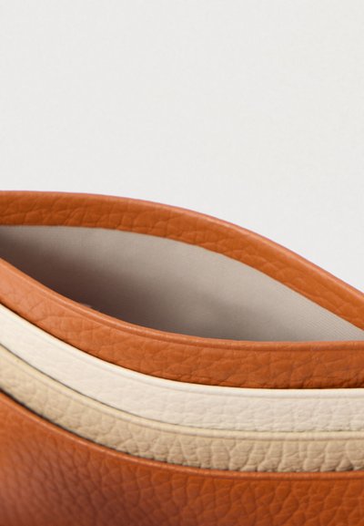 Chaussure en cuir avec un design arrondi et bas. Présente un extérieur orange et deux rayures crème le long du bord. Doublure intérieure lisse.