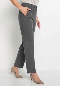 Grau maßgeschneiderte Hose mit glatter Textur, ausgestattet mit einem Bund und Seitentaschen. Kombiniert mit hellbeigen Absätzen.