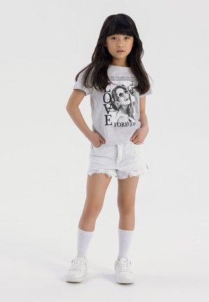 Szary t-shirt z krótkim rękawem z nadrukowanym grafikiem i tekstem, w połączeniu z białymi zniszczonymi szortami dżinsowymi i białymi trampkami oraz skarpetkami za kostkę.