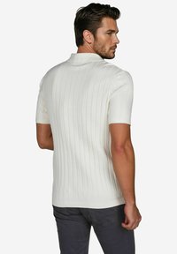 Weißes, geripptes Poloshirt mit kurzen Ärmeln und Kragen, das eine vertikale Textur und eine taillierte Silhouette aufweist.