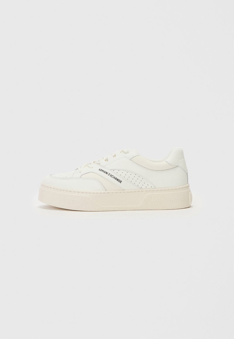 Vit sneaker med plattformssula, tillverkad av slätt läder. Har perforerade sidopaneler och varumärkning på utsidan.