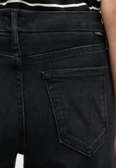 Μαύρο τζιν με τσέπη στο πίσω μέρος που έχει ανάγλυφο το γράμμα 'M', υφή υφάσματος και κανονική ραφή. Απλός σχεδιασμός χωρίς διακοσμήσεις.