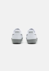 Nike tossud valges ja hallis, millel on sile pealispind, pehmendatud konts ja tekstuuriga tallad, millel on ulatuslikud haarde detailid.