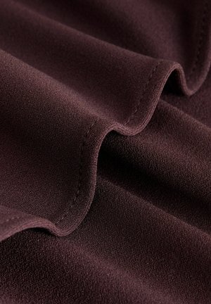 Dunkelburgunderfarbener Stoff mit einer weichen, strukturierten Oberfläche, die glatte, fließende Falten und einen sauberen Saum entlang der Kanten aufweist, ohne sichtbare Muster.