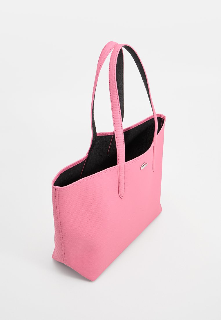 Rote Lederhandtasche mit schwarzem Innenfutter, rechteckiger Form, zwei Griffen und einem kleinen Logo-Akzent auf einer Seite. Glatte Textur.