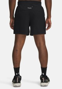 Schwarze Sportshorts mit einem Kordelzugbund, ausgestattet mit Seitentaschen und einem glatten, leichten Stoff. Minimale Branding auf der Rückseite.