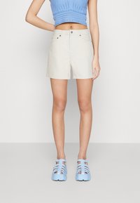Shorts de couleur crème avec une coupe classique, dotés d'une taille et de poches avant. Associés à un haut en tricot côtelé bleu et des chaussures bleu clair.