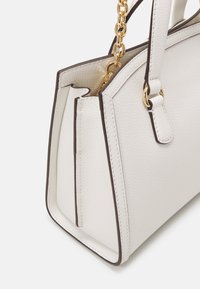 Biała skórzana torebka o teksturowanej powierzchni, z ciemnobrązowymi wykończeniami i złotym sprzętem łańcuchowym. Charakteryzuje się ustrukturyzowanym kształtem oraz dwoma ramiączkami.