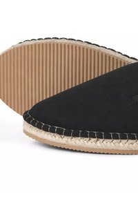 Black canvas slip-on shoe with a rounded toe, featuring a jute-style trim and textured rubber sole with ribbed pattern.