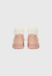 Rosa läder ankelskor med en fluffig vit krage, snördetaljer och en texturerad gummisula med djupa spår för grepp.