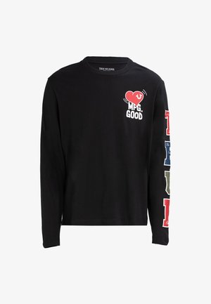 Zwart shirt met lange mouwen met de tekst "MFG. GOOD" en een rode hartafbeelding op de borst, kleurrijke blokletters die verticaal langs de rechtermouw lopen.